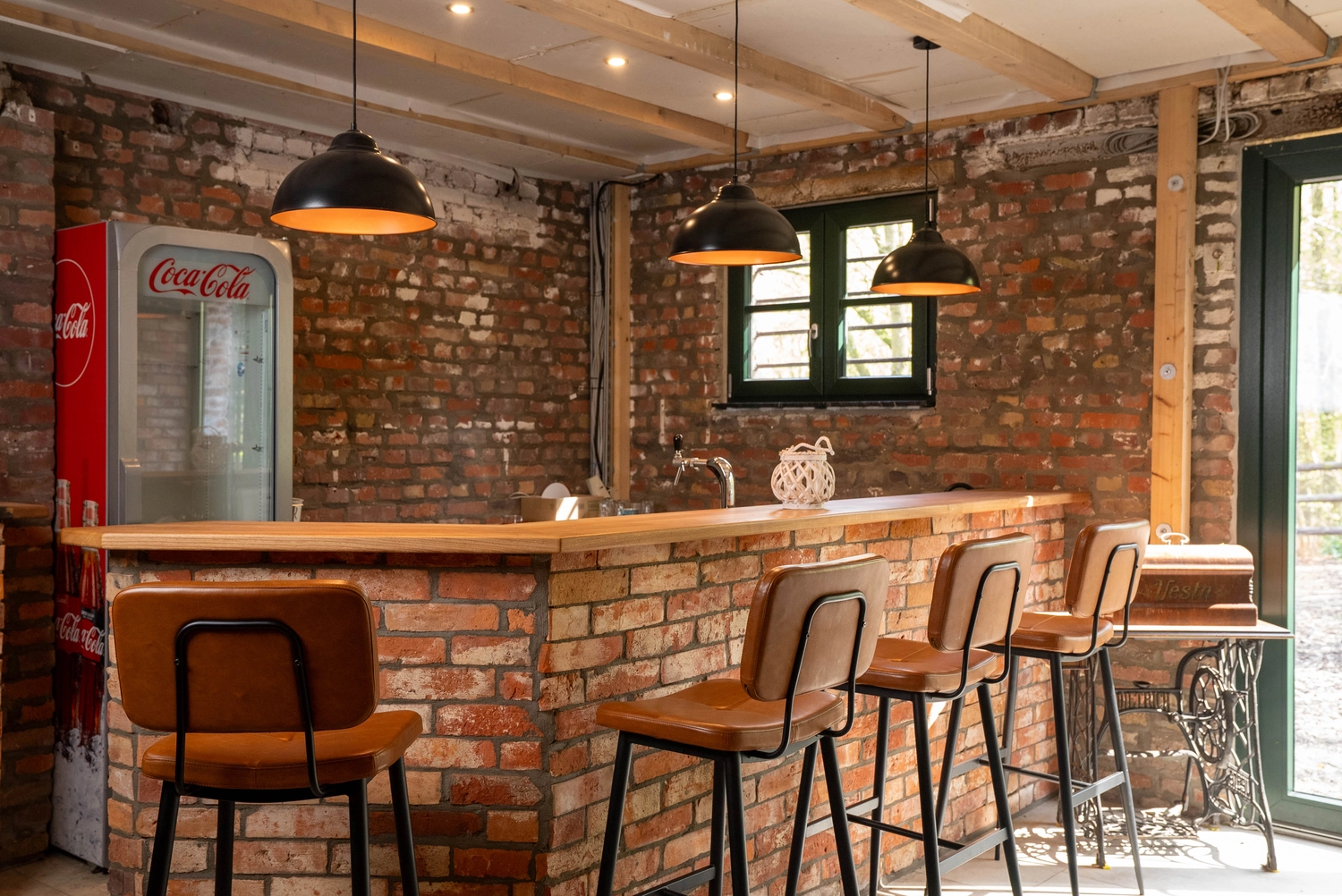 Alpakahof Dingen – Alpaka-Trekking – Das Bild zeigt eine ländliche Bauernhofszene mit Alpakas in einem hölzernen Unterstand und Gehege.