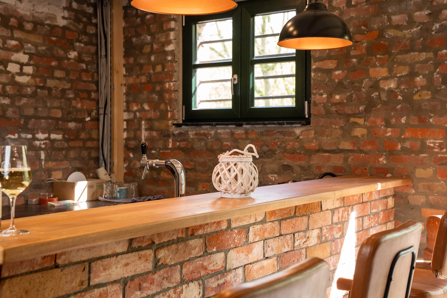 Alpakahof Dingen – Alpaka-Trekking – Das Bild zeigt eine ländliche Bauernhofszene mit Alpakas in einem hölzernen Unterstand und Gehege.