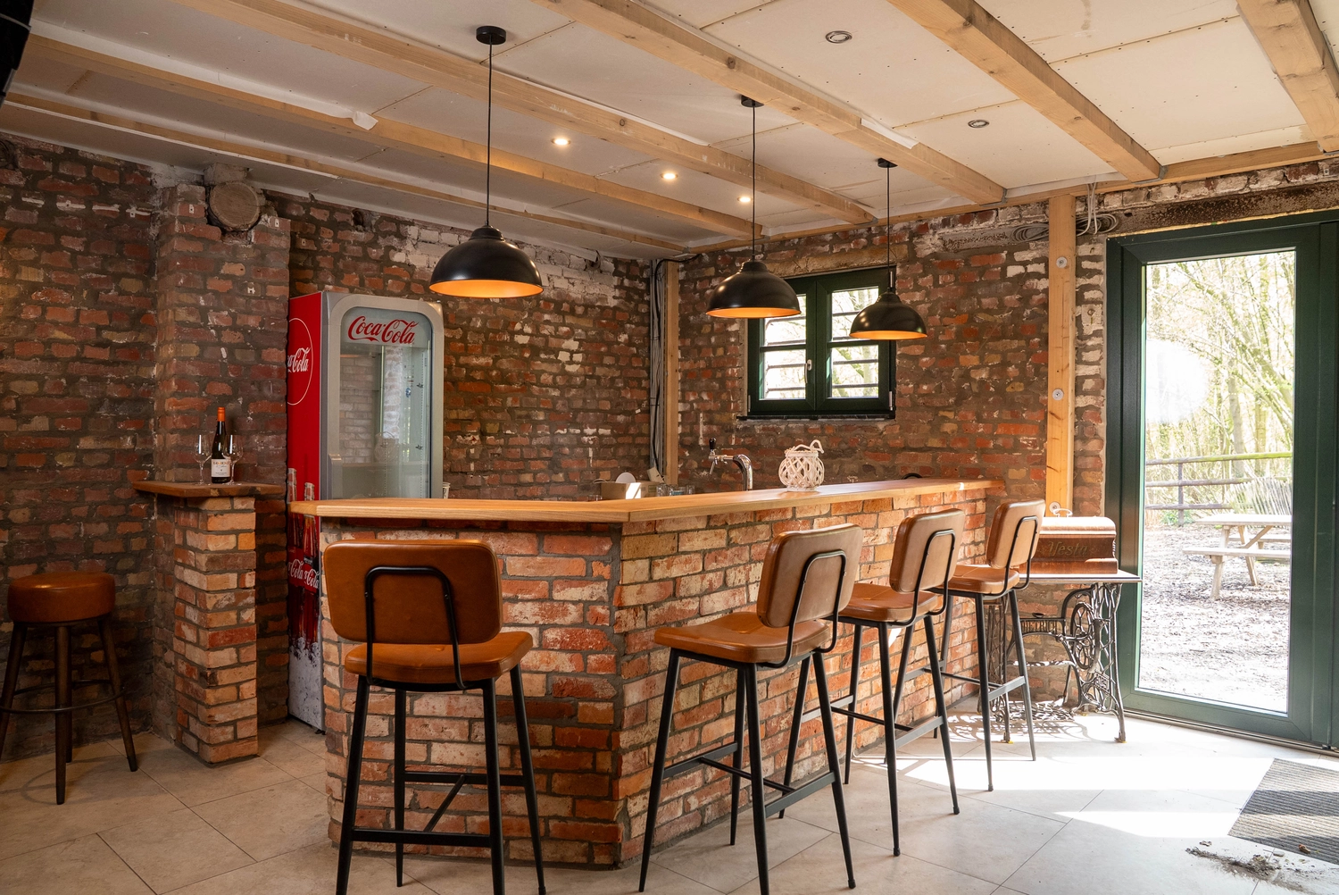 Alpakahof Dingen – Alpaka-Trekking – Das Bild zeigt eine ländliche Bauernhofszene mit Alpakas in einem hölzernen Unterstand und Gehege.