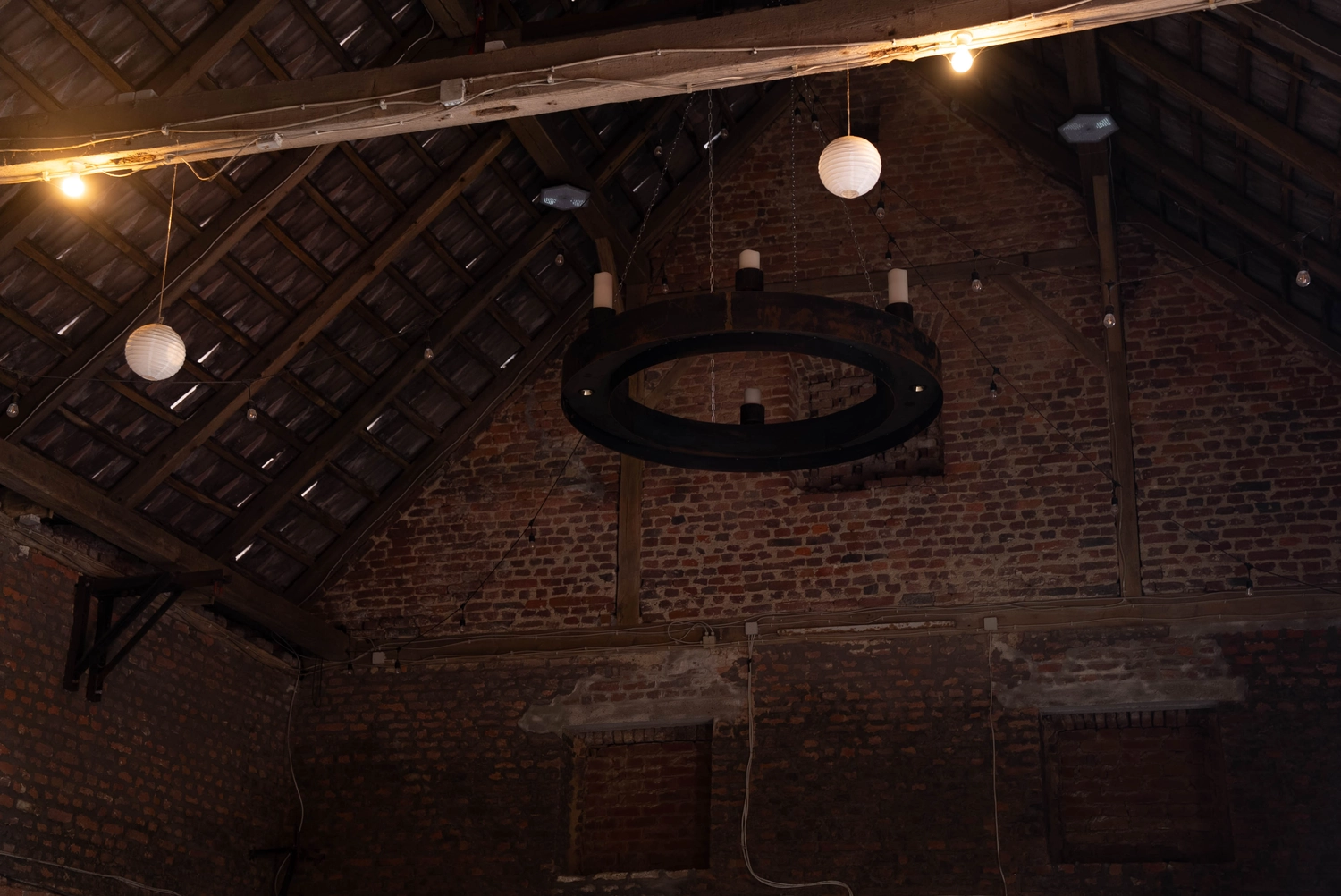 Alpakahof Dingen – Alpaka-Trekking – Das Bild zeigt eine ländliche Bauernhofszene mit Alpakas in einem hölzernen Unterstand und Gehege.