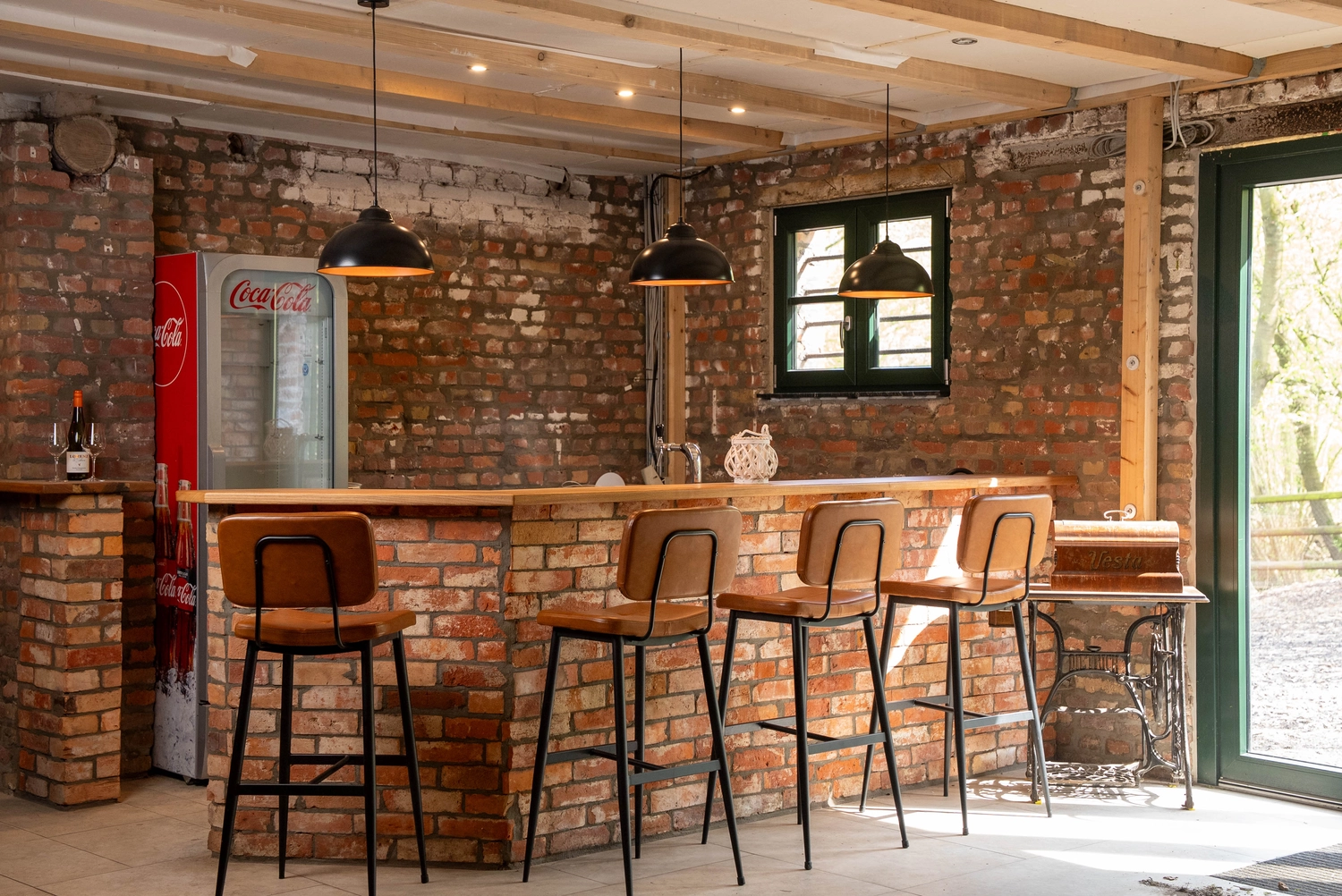 Alpakahof Dingen – Alpaka-Trekking – Das Bild zeigt eine ländliche Bauernhofszene mit Alpakas in einem hölzernen Unterstand und Gehege.